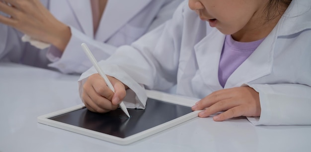 Niño asiático aprendiendo con un médico en el laboratorio. Examen físico y clase de educación científica.