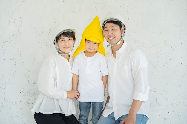Niño asiático con capuchas de prevención de desastres y padres con cascos