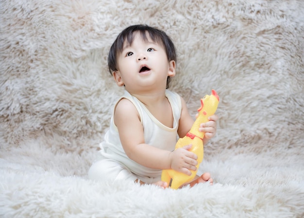 Un niño asiático divirtiéndose jugando al chillido de goma de juguete Pollo amarillo