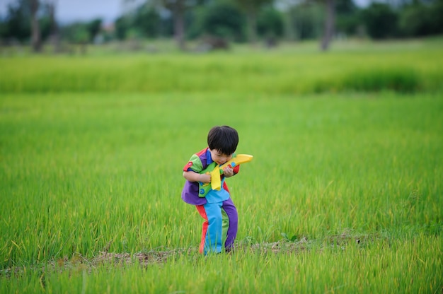 Niño asiático divirtiéndose con música en el campo de arroz verde