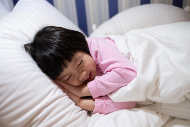 niño asiático dormir en la cama niño enfermo