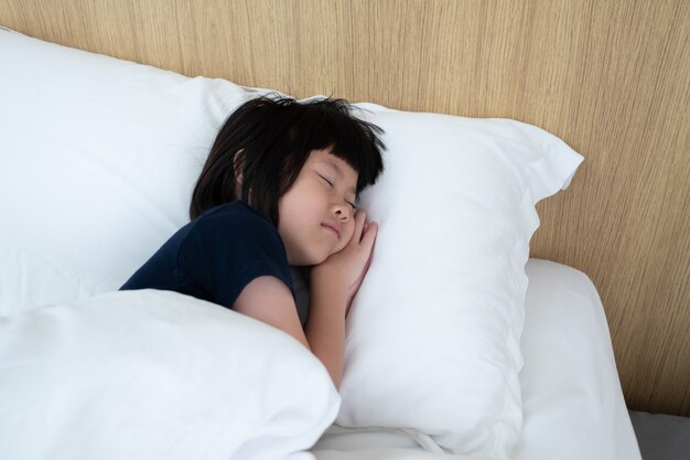 niño asiático duerme en la cama, niño enfermo