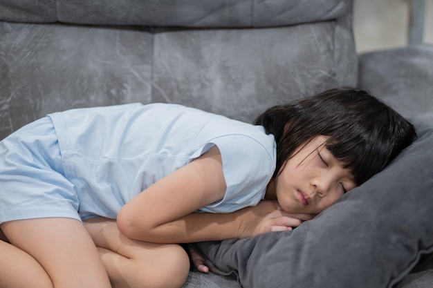 Niño asiático duerme en la cama, niño enfermo