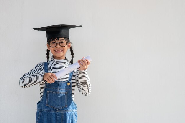 Foto un niño asiático feliz se gradúa con una gorra de graduación.