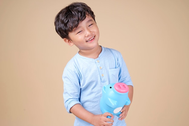 Niño asiático feliz con hucha rosa