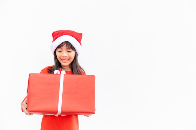 Niño asiático feliz en Santa sombrero rojo con regalos de Navidad. Tiempo de navidad sobre fondo blanco.