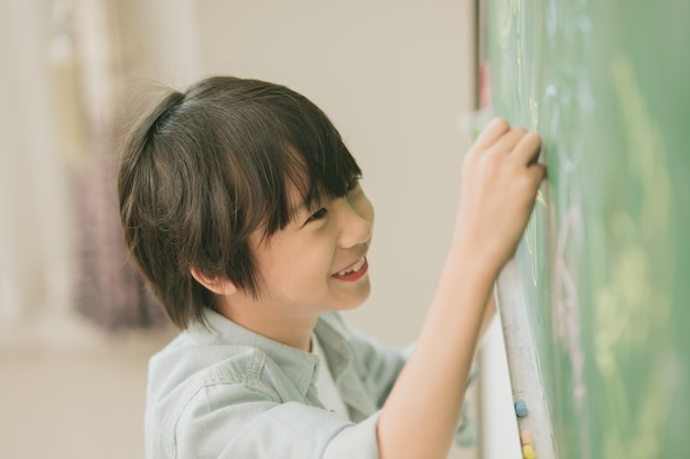 Niño asiático feliz sonrisa disfrutar de la educación en la escuela en el aula escribiendo respuesta en pizarras