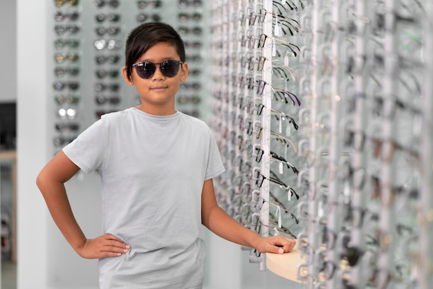 Un niño asiático con gafas de sol en una tienda de gafas