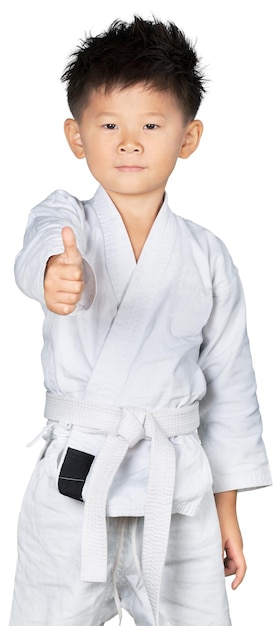 Niño asiático de Karate en kimono blanco con el pulgar hacia arriba en el fondo