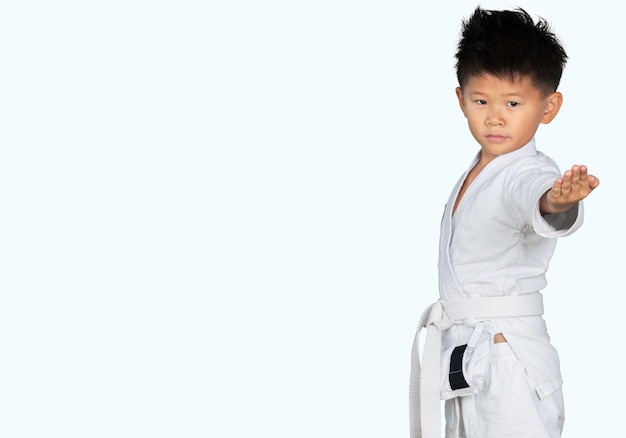 Foto niño asiático de karate en kimono blanco sobre fondo