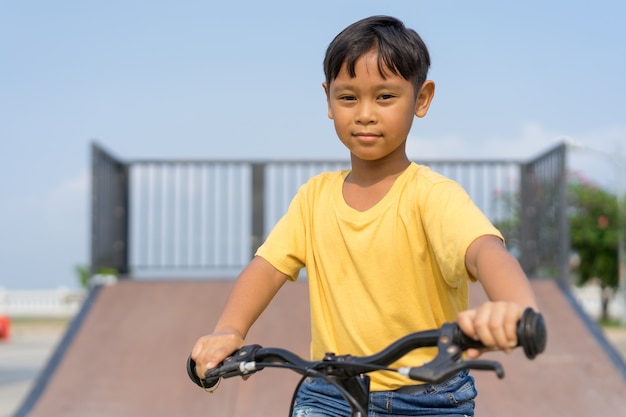 niño asiático montando bicicleta en parque público