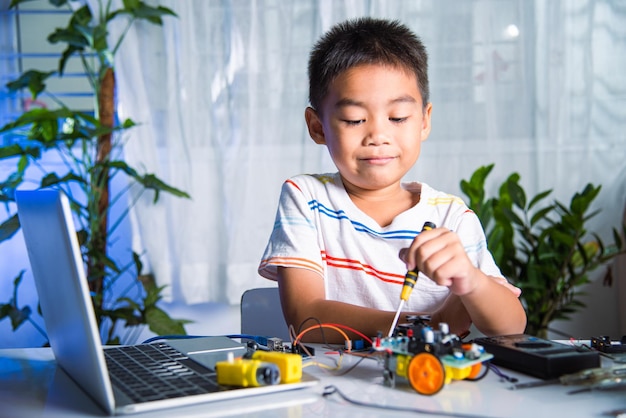 Niño asiático montando el proyecto de tareas del coche robot Arduino en casa