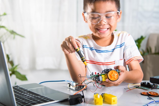 Niño asiático montando el proyecto de tareas del coche robot Arduino en casa