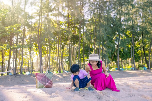 Niño asiático y mujer mamá relajándose en la playa tropical disfrutan de la libertad y el aire fresco con un elegante sombrero y ropa Feliz turista sonriente en los trópicos en vacaciones de viaje