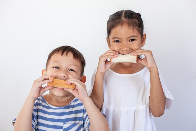 Niño asiático niño y niña comiendo pan juntos antes de ir a la escuela