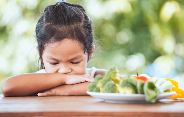 A un niño asiático no le gusta comer verduras y se niega a comer verduras saludables