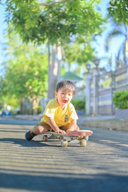 Niño asiático en patineta.El niño aprende a patinar