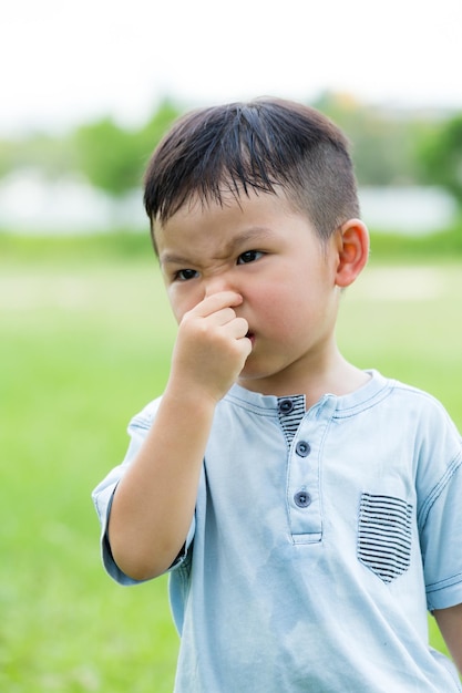 Un niño asiático con picazón en la nariz.