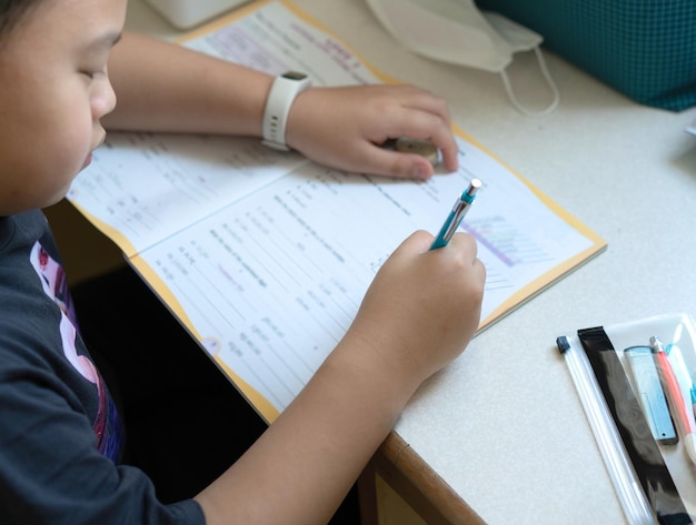 Niño asiático sentarse y escribir la tarea en casa