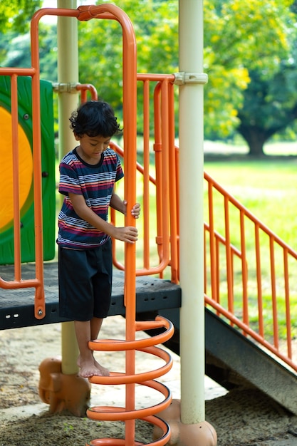 Un niño asiático se sube a un equipo de juegos en una escuela.