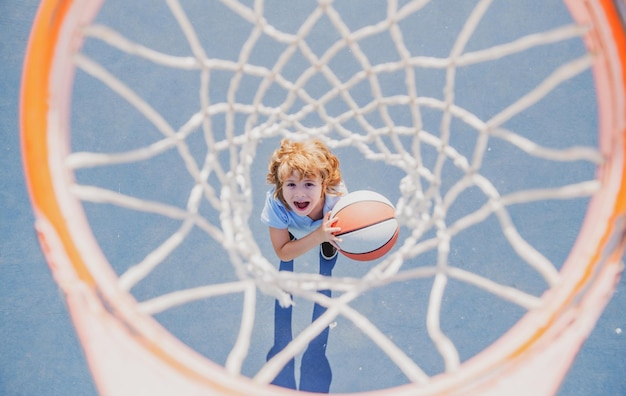 Niño asombrado jugando baloncesto sosteniendo la pelota con cara feliz