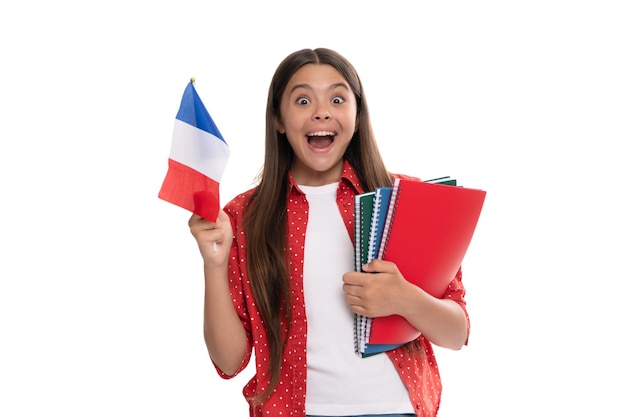 Niño asombrado sostiene la bandera francesa y el cuaderno escolar para estudiar aislado en blanco estudiar en el extranjero