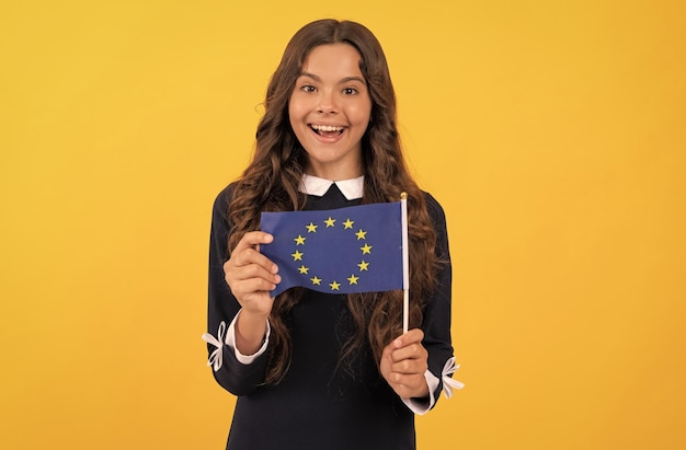 Niño asombrado sostiene la bandera de la unión europea fondo amarillo unión europea