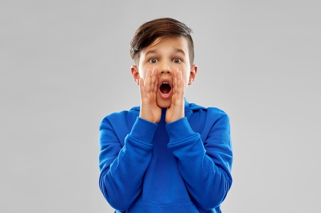 Foto niño asustado con sudadera azul gritando o llamando