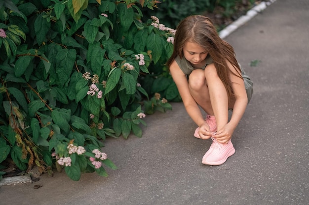 Niño ata los cordones de las zapatillas rosas