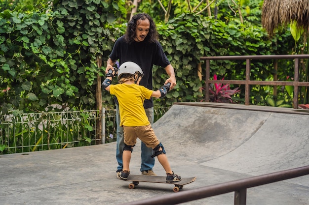 Niño atlético aprende a andar en patineta con un entrenador en un parque de patinaje Deportes educativos para niños