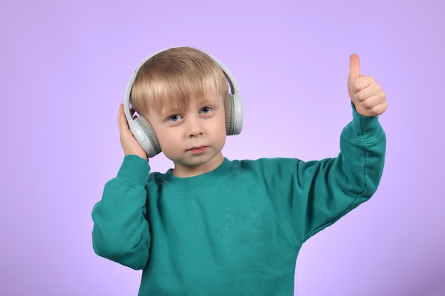 Un niño con audífonos y un suéter verde está dando un pulgar hacia arriba.