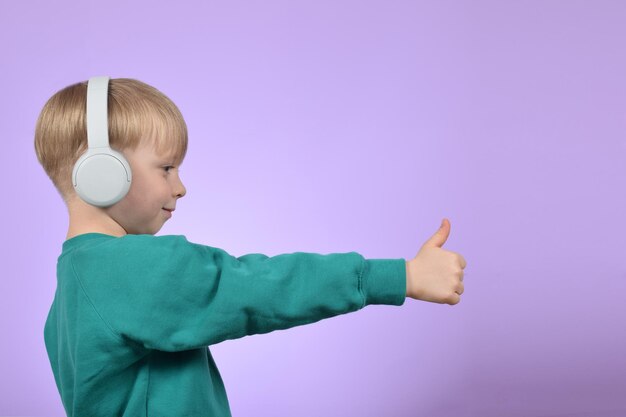 Un niño con auriculares y una camisa verde está dando un pulgar hacia arriba.