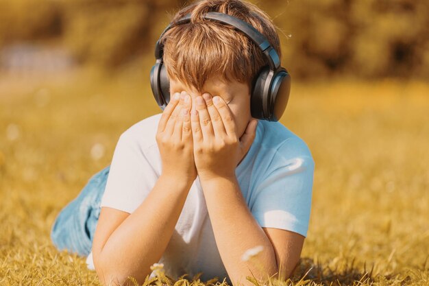 Niño con auriculares escuchando música en el césped del parque