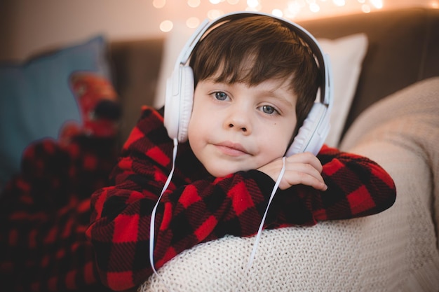 Un niño con auriculares está acostado en el estilo de vida del sofá El niño escucha música