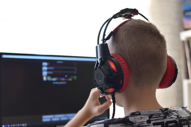 Un niño con auriculares se sienta en una computadora jugando juegos en línea. adicción al juego infantil.