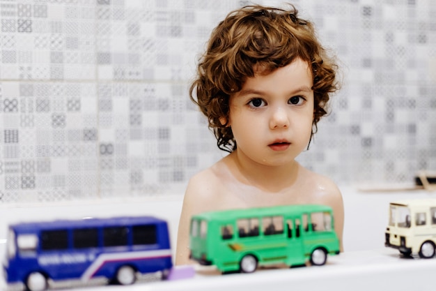 Niño autista en el baño jugando con bus de juguete