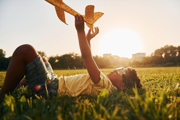 Niño con avión de juguete Niño afroamericano divertirse en el campo durante el día de verano