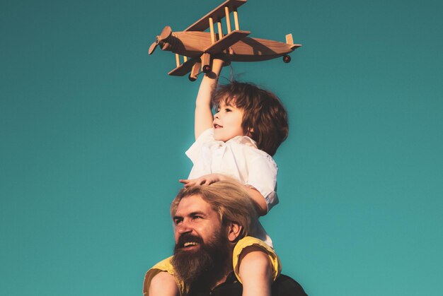 Niño con avión sentado sobre los hombros del padre Padre e hijo juntos Niño está sentado sobre el hombro de papá a cuestas mientras el vuelo