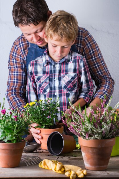 Niño ayuda al padre a plantar flores tiempo familiar en casa