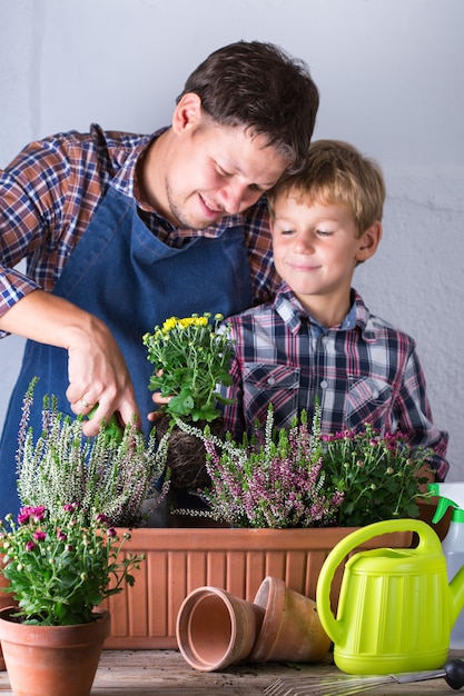 Niño ayuda al padre a plantar flores tiempo familiar en casa