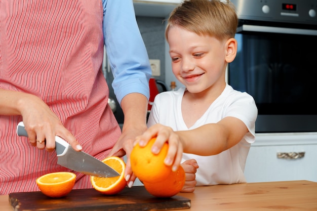 Niño ayuda a su mamá a cortar naranjas