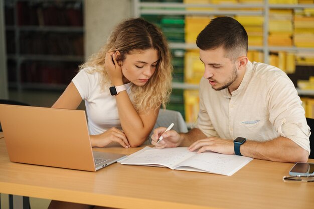 Foto el niño ayuda a su novia a prepararse para el examen en el concepto de educación de la biblioteca pública