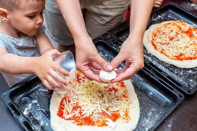 Niño ayudando a la madre a cocinar pizza en casa