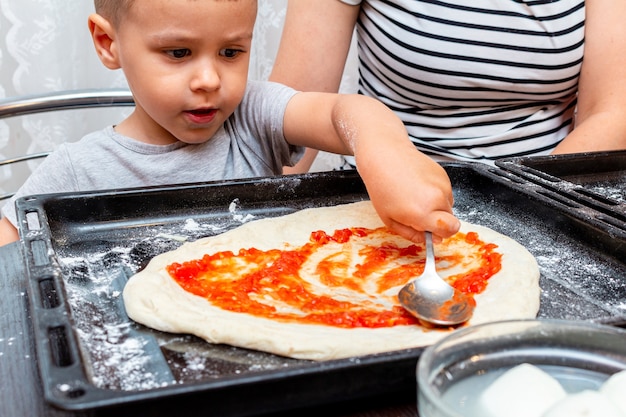 Niño ayudando a la madre hace pizza en casa