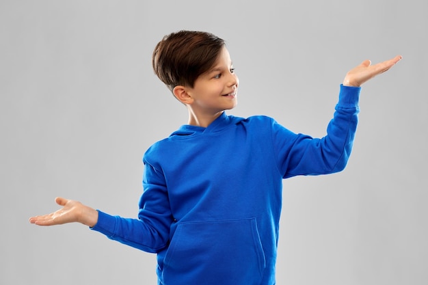 Foto niño de azul sosteniendo algo en manos vacías