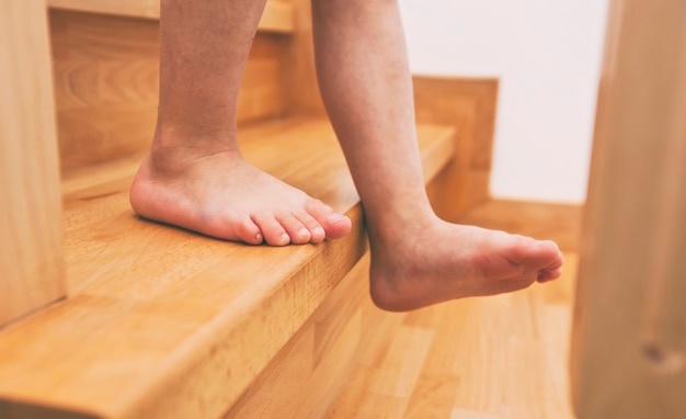 El niño baja por las escaleras de madera en casa.