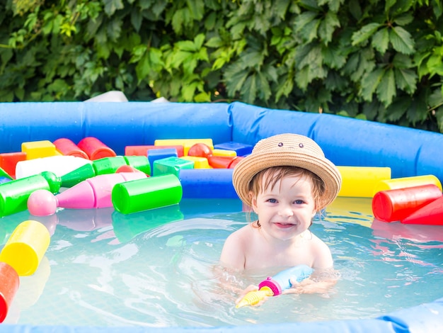 El niño se baña en una piscina hinchable, juega y salpica