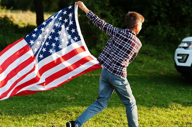 Foto niño con bandera de estados unidos al aire libre. américa celebrando.