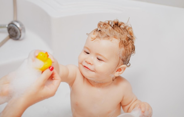 Niño baño de burbujas divertido bebé niño bañado en espuma y lavado en la bañera en casa