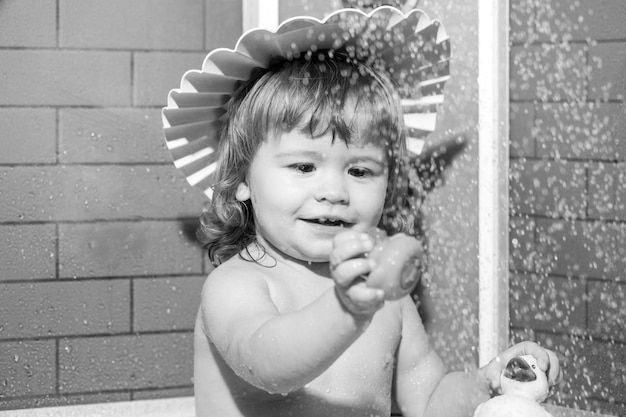 Foto niño en el baño juega con espuma lindo bebé disfrutando del baño y bañado en el baño